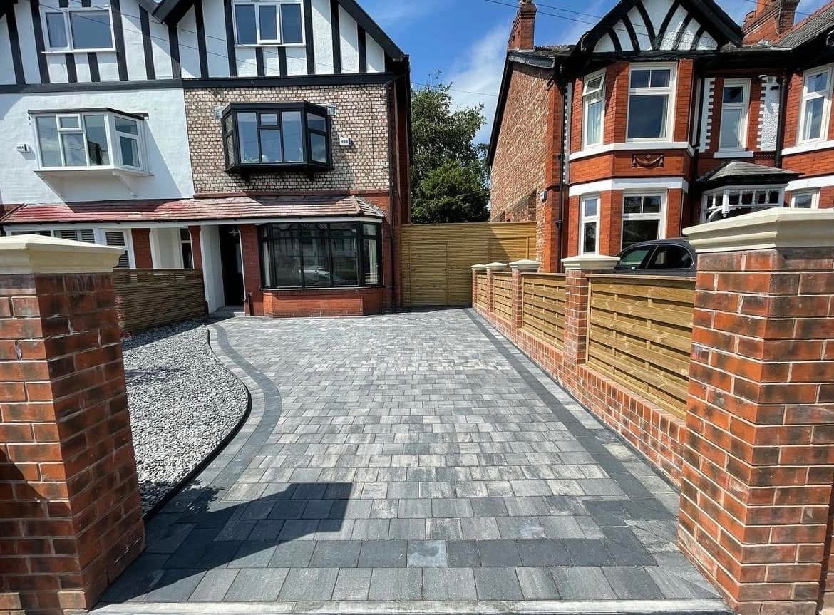 Grey block paved driveway between brick pillars